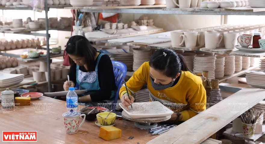 Deux artisans en train de décorer leur produit. 