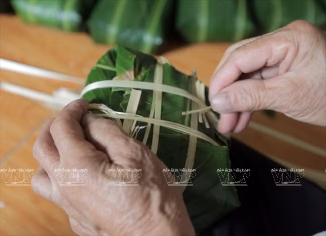 Le bánh chưng est noué avec des ficelles avant d’être cuit dans l’eau bouillante.