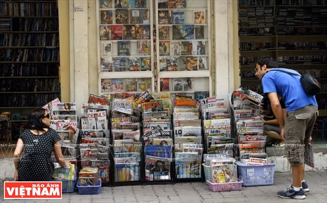 Un étranger cherchant des journaux à une boutique sur le trottoir.