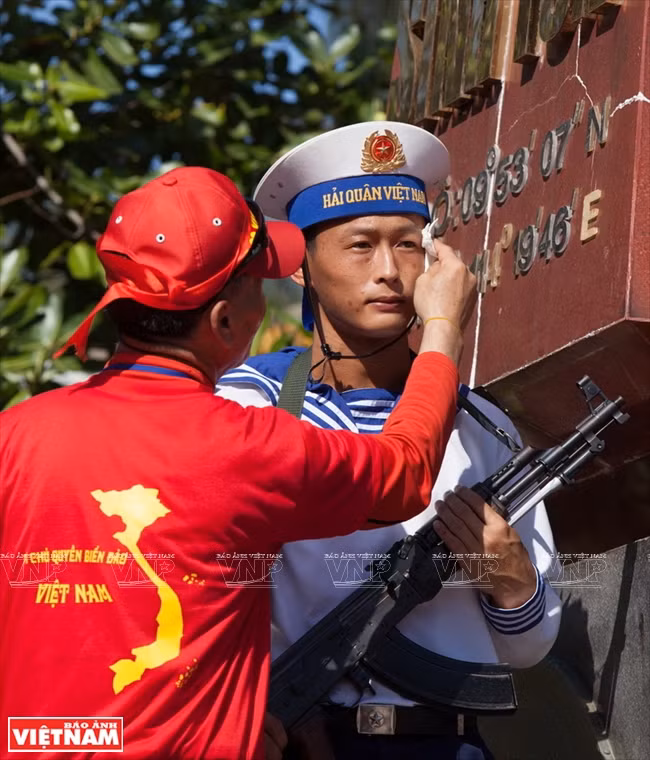​Ce Vietnamien de République de Corée éponge le visage en sueur d’un soldat en ​charge de garder une stèle marquant la souveraineté nationale sur l’île de Sinh Tôn.