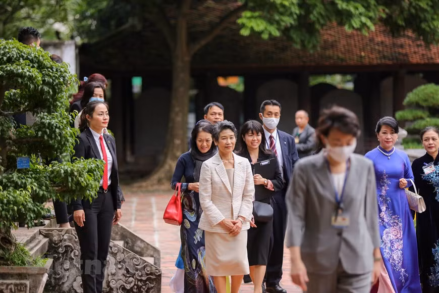 Suga Mariko, Trân Nguyêt Thu et des délégués se promènent dans l'espace du temple. Ce temple, qui n'avait pas de but strictement religieux, servait d'académie confucéenne. Il a été fondé en 1070 par le troisième empereur de la dynastie Ly (Lý Thánh Tông), à l'époque où la ville s'appelait Thang Long. C'est ici que les fils de sang royal, les fils de mandarins et de l'aristocratie poursuivaient leurs études pour devenir lettrés et hauts fonctionnaires, c'est-à-dire les « Fils de la Nation » (Quôc Tu Giam). À partir de 1165, les lauréats reçurent le titre de « grand lettré ». Les trois premiers du concours reçurent en plus un titre spécifique à partir de 1247. Les femmes ne pouvaient pas assister au concours.