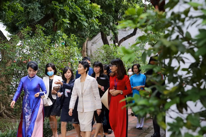 Suga Mariko s'est rendue au Temple de la Littérature dans le cadre de sa visite au Vietnam avec son époux. Le temple a été fondé en 1070 par le troisième empereur de la dynastie Ly, Lý Thánh Tông, à l'époque où la ville s'appelait Thang Long. Le temple de la Littérature se trouve au sud de la cité impériale de Thang Long. Il s'étend sur une superficie de 54 000 mètres carrés, y compris le lac de la Littérature (Ho Van Chuong) et le parc Giam. Le temple est divisé en cinq cours intérieures séparées par des murs selon l'axe traditionnel chinois nord-sud. L'allée principale avec des portes étaient réservée aux seigneurs, tandis que les petites allées de côté servaient aux domestiques, serviteurs et soldats. 