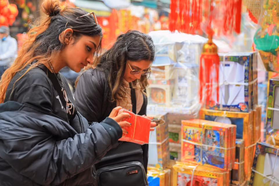 Des touristes étrangers achètent des enveloppes pour l'argent porte-bonheur dans la rue Hang Ma. Photo : VNA 