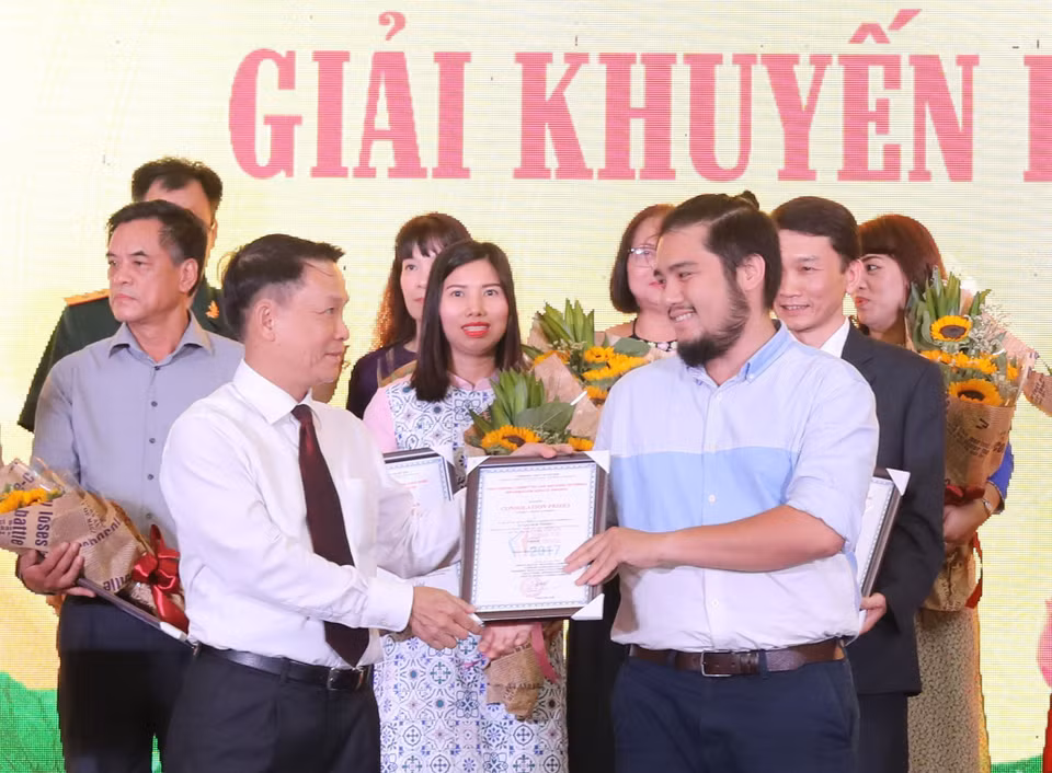 Nguyen Duc Loi, directeur général de l'Agence vietnamienne d'Information (gauche) remet le prix d'encouragement 