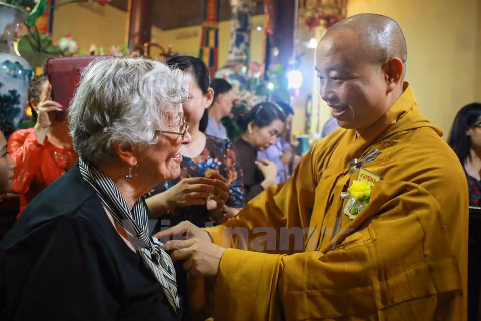 Le bonze Thich Thanh Nhieu met une rose blanche sur le vêtement de la mère de l'ambassadeur Ted Osius. 