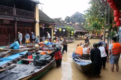 Des touristes prennent des petits barques pour visiter la vieille ville de Hôi An encore inondées. Photo : VNA