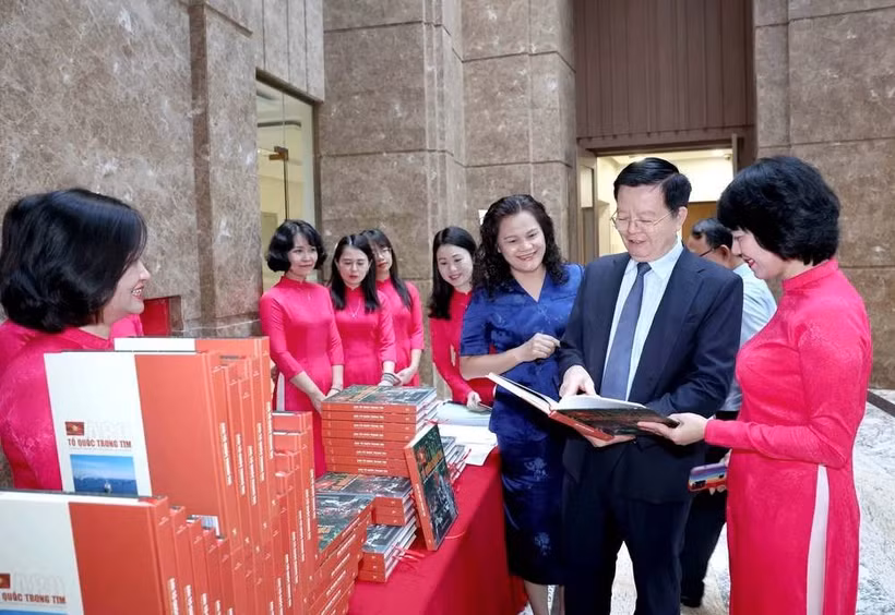 Le vice-Premier ministre Mai Van Chinh apprécie le livre photo « A80 : la Patrie dans le cœur ». Photo: VNA