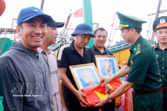La Fédération et le Commandement provincial des gardes-frontières ont remis aux pêcheurs 400 drapeaux nationaux et 120 portraits du Président Hô Chi Minh. Photo: VNA