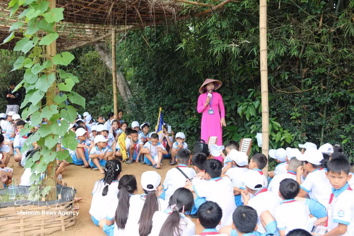 Des enfants écoutaient avec attention le guide qui expliquait l'enfance du président Hô Chi Minh. Photo: VNA